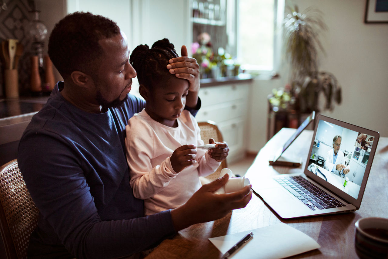 Father and daughter on telehealth call at home