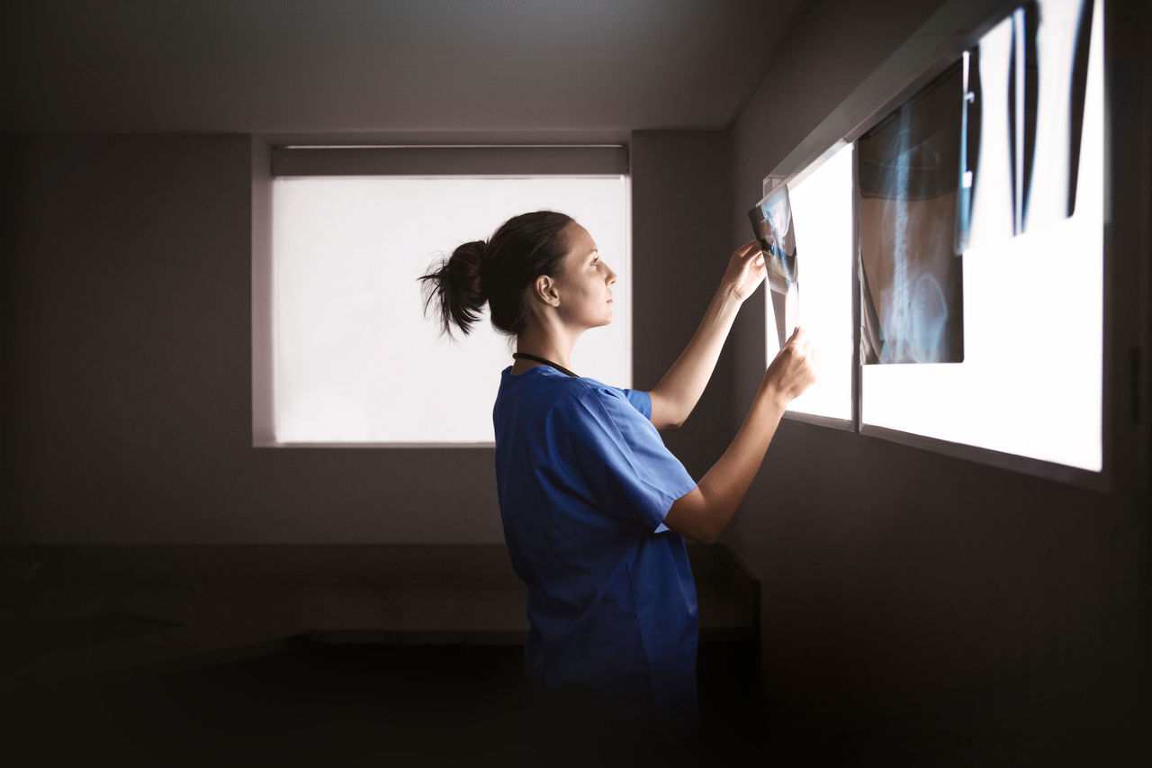 female radiologist reviewing slides in dark room