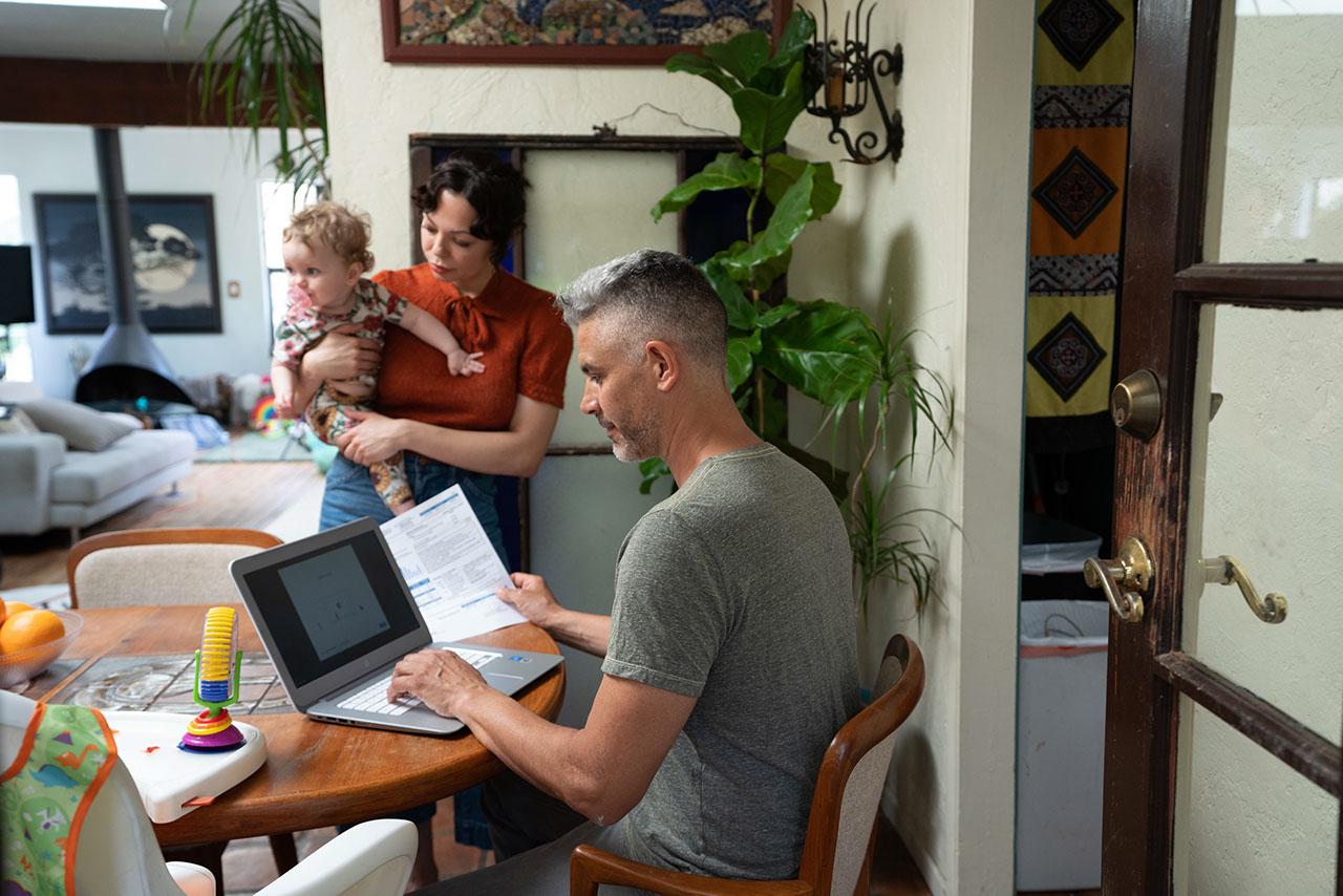 Family at home, husband on laptop