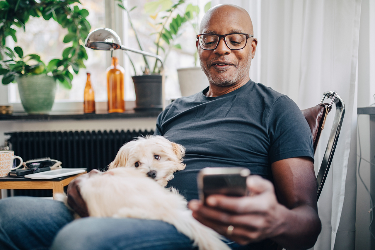 Man looking at mobile at home with dog