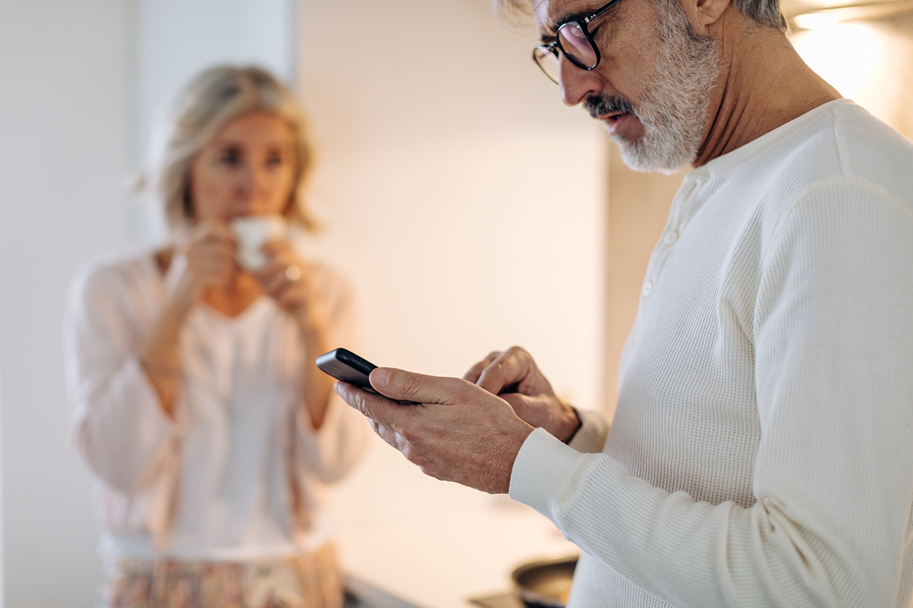 Mature man with wife using cell phone in kitchen at home