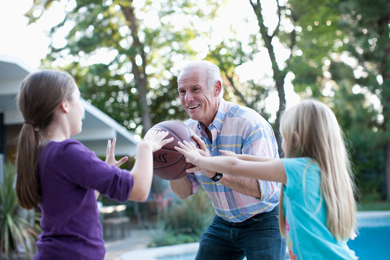 Older man playing basketball with granddaughters
