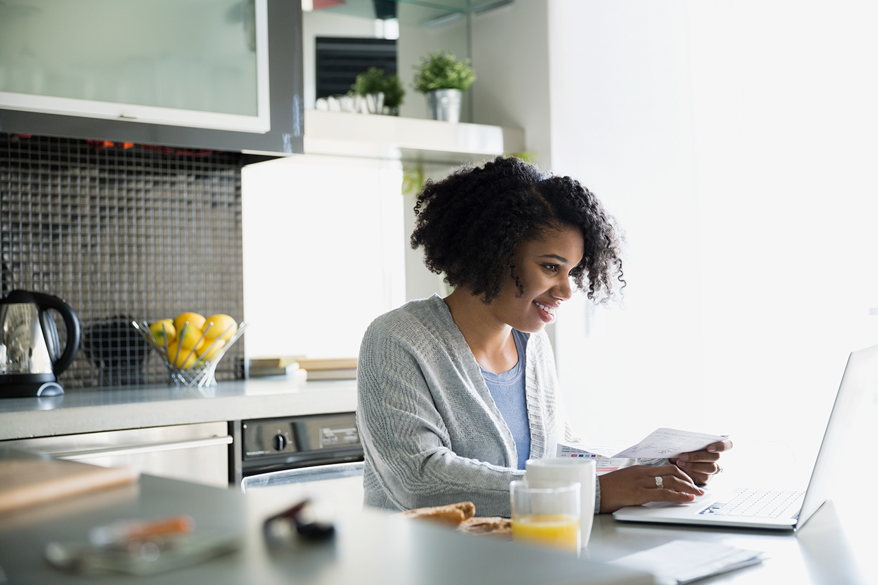 Woman paying bills online in morning kitchen