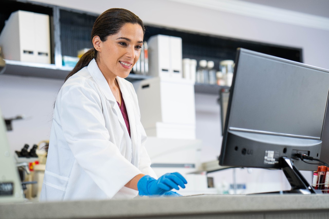 Female laboratory technician looking at computer monitor and smiling
