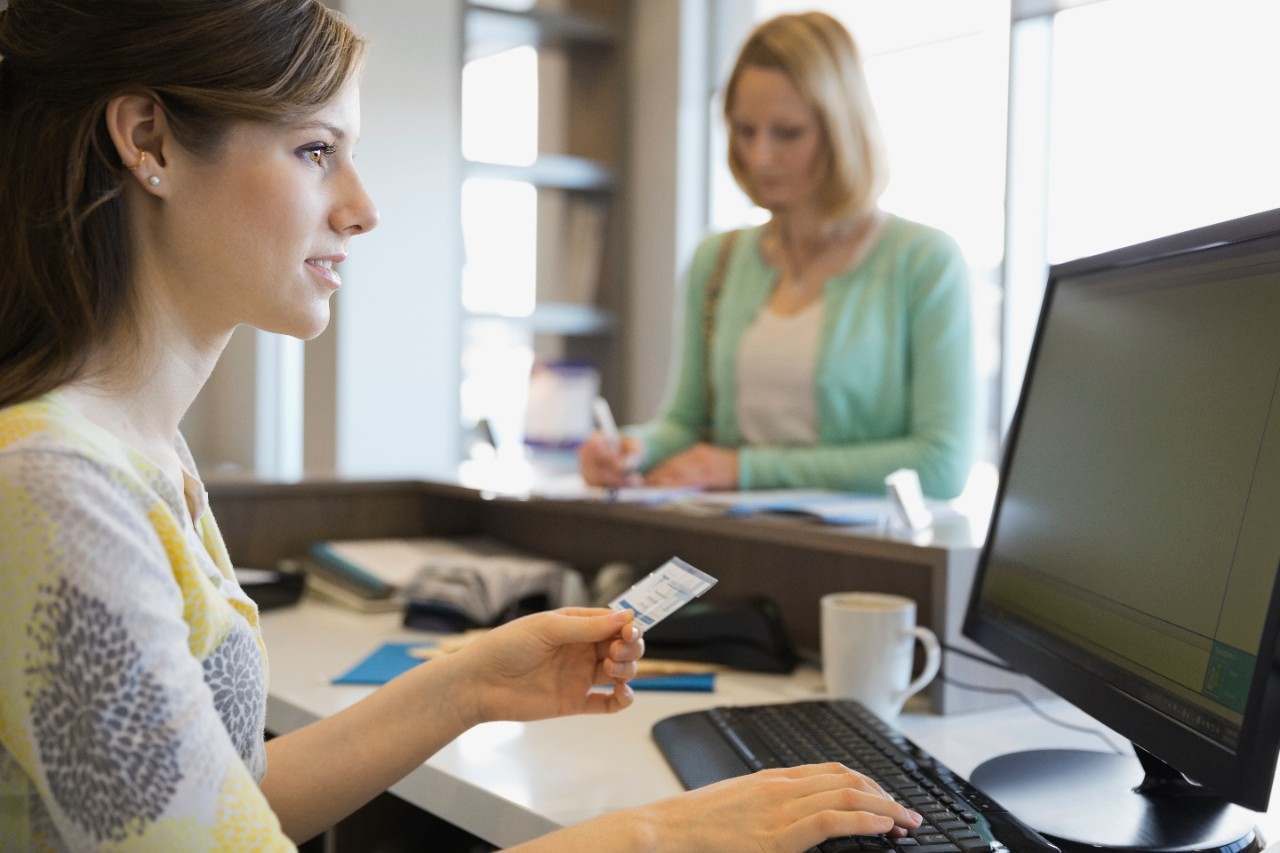 Patient paying female receptionist for Medical Visit with credit card