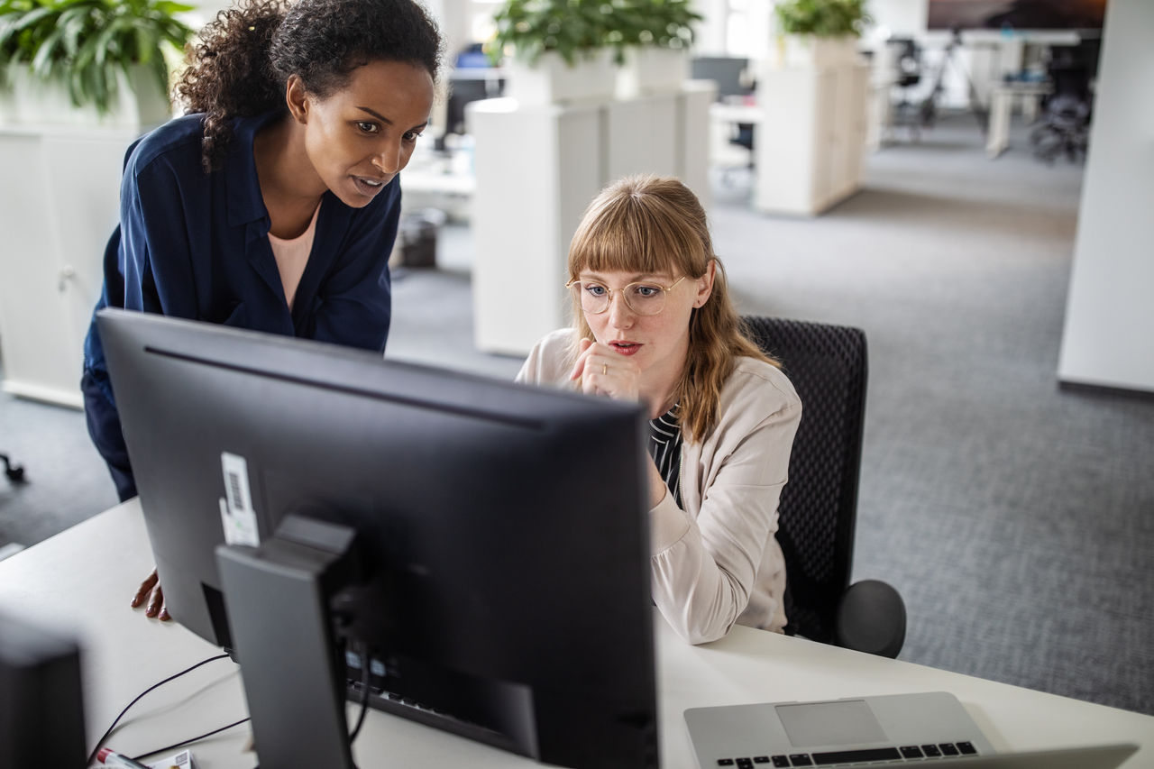 Two businesswomen looking at computer in open office