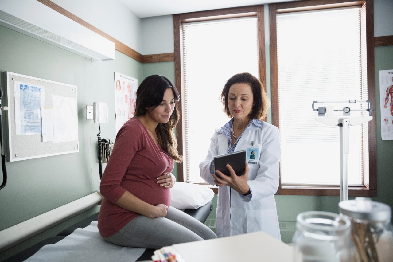 Pregnant woman with provider looking at tablet