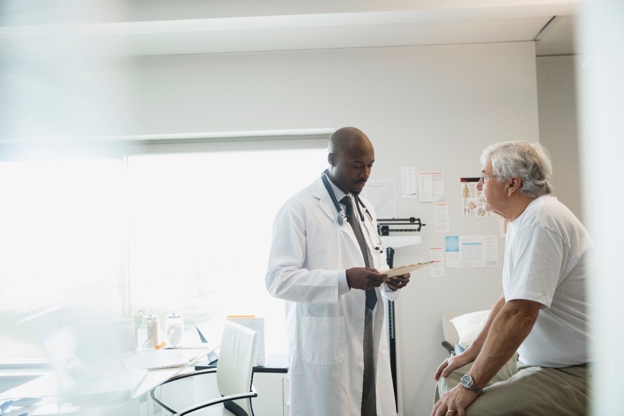 Doctor reviewing medical chart with senior man