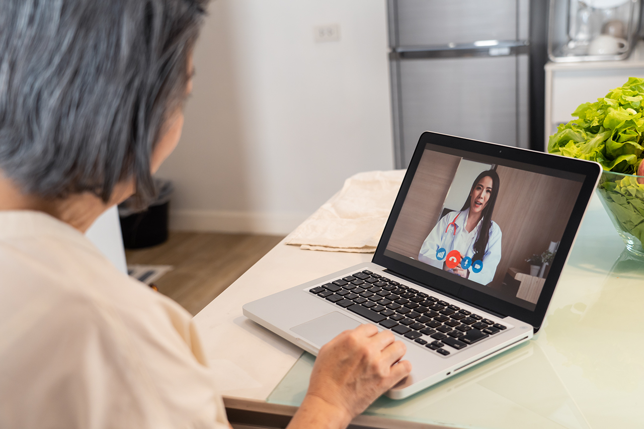 Senior woman video call with doctor in living room at home