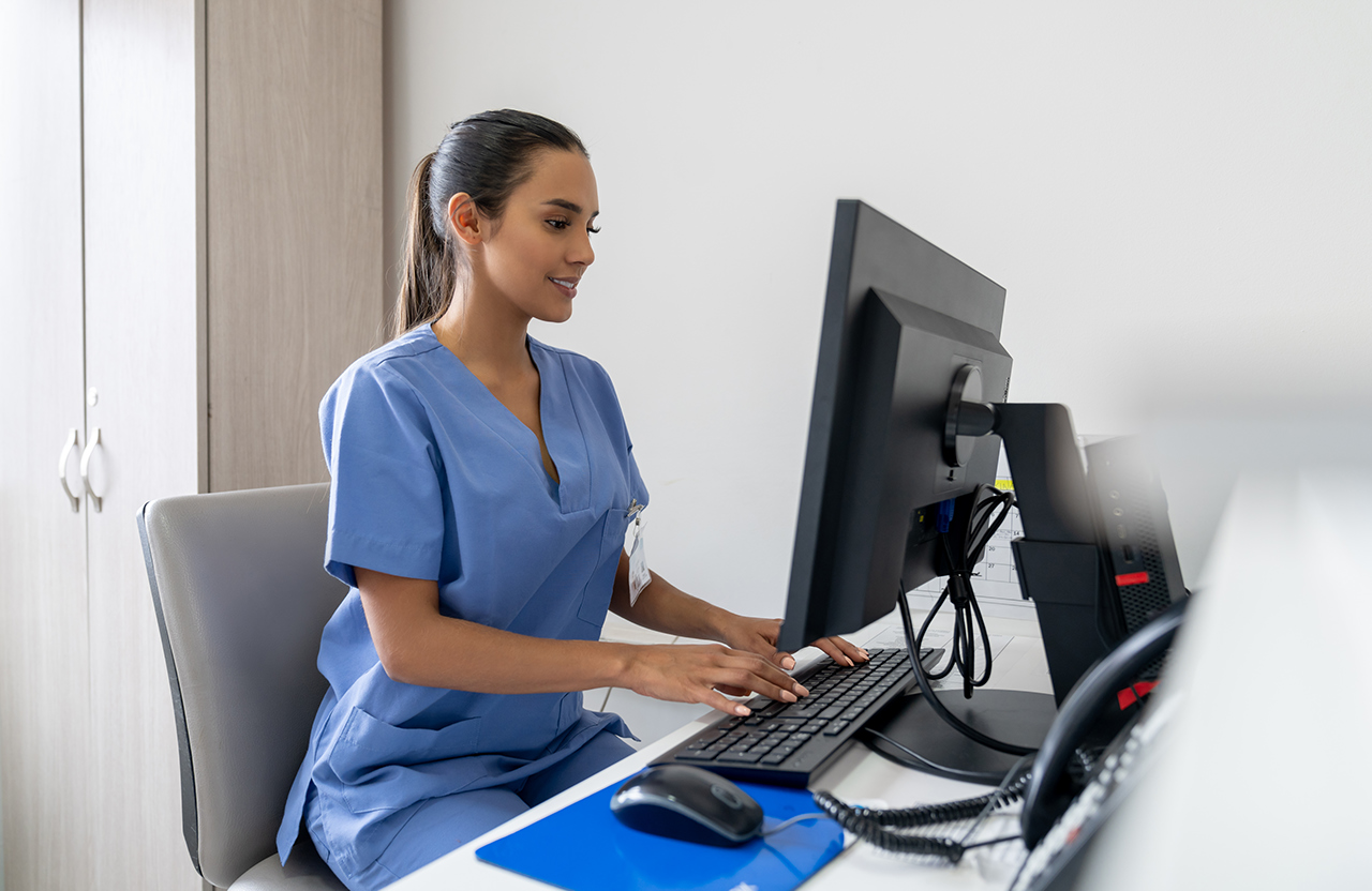 Receptionist working at a hospital using computers and looking happy - healthcare workers concepts, dental, coding, computer