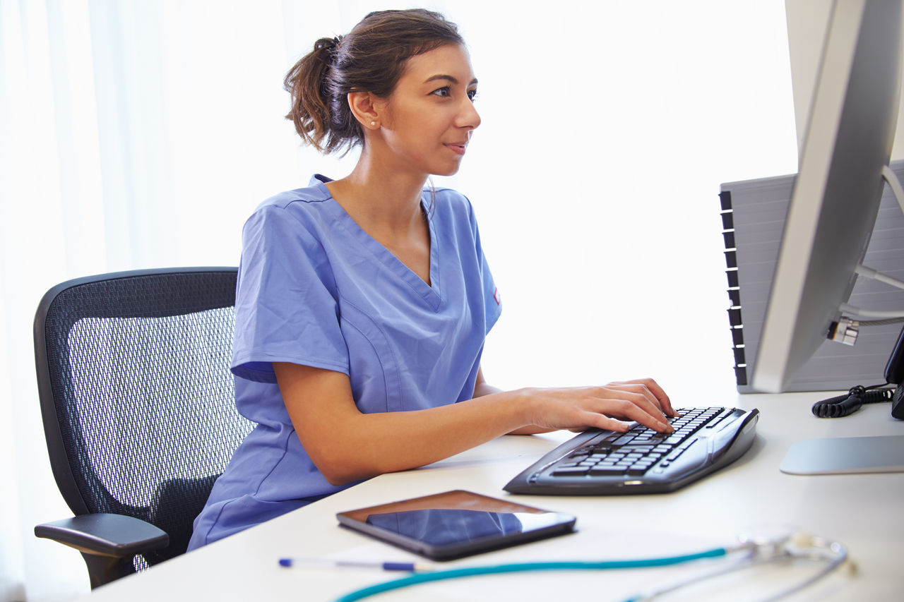 Female Doctor In Office Working At Computer